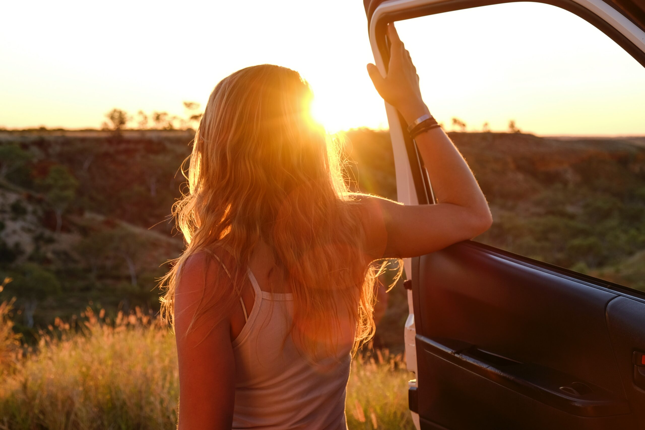 A woman enjoying the sunset from her rental car
