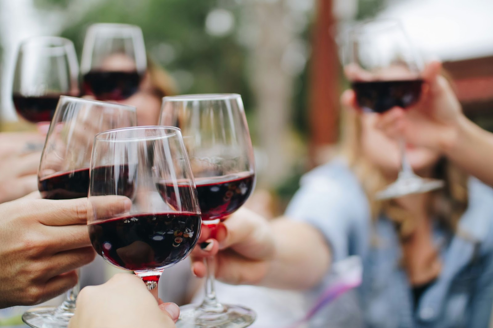 A close-up picture of friends enjoying a glass of local red wine